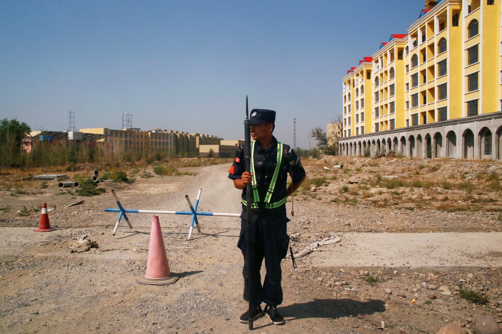 A Chinese police officer takes his position by the road near a vocational education centre in Yining in Xinjiang, Uighur Autonomous Region, China, September 4, 2018. Reuters / Thomas Peter