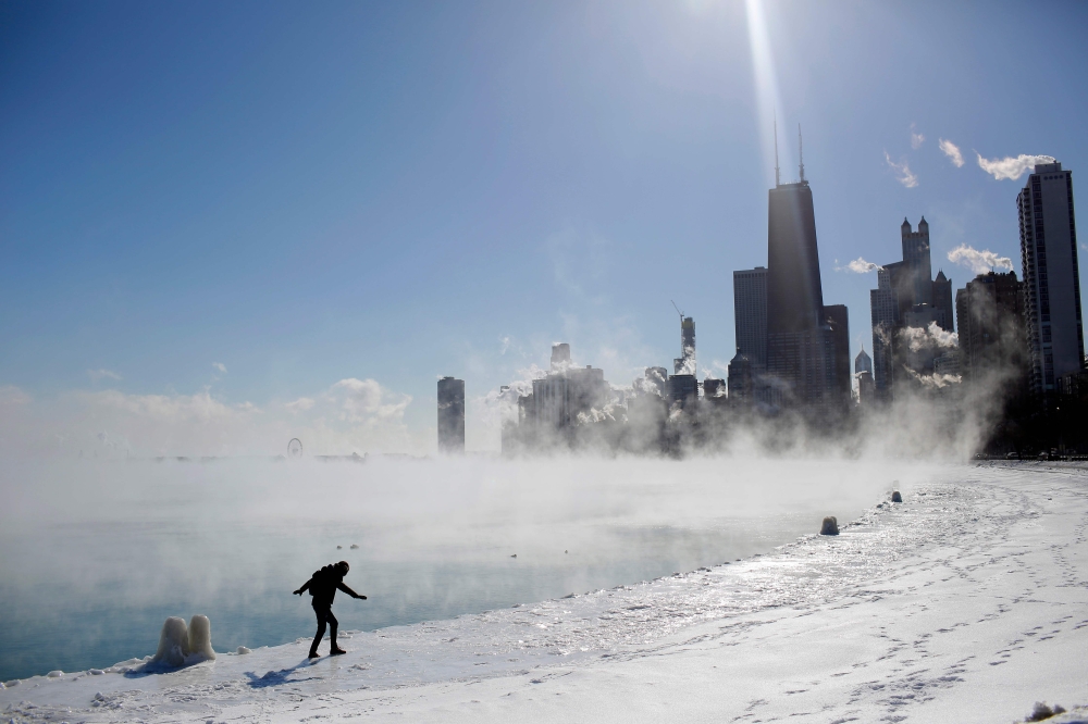 FILE PHOTO: A man keeps his balance as he walks on the edge of Lake Michigan's shore line as temperatures dropped to -20 degrees F (-29C) on January 30, 2019 in Chicago, Illinois.  AFP / Joshua Lott 