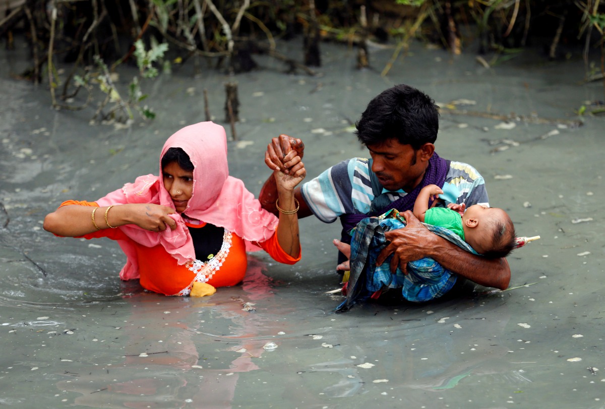 Rohingya refugees carry their child as they walk through water after crossing border by boat through the Naf River in Teknaf, Bangladesh, September 7, 2017. Reuters / Mohammad Ponir Hossain