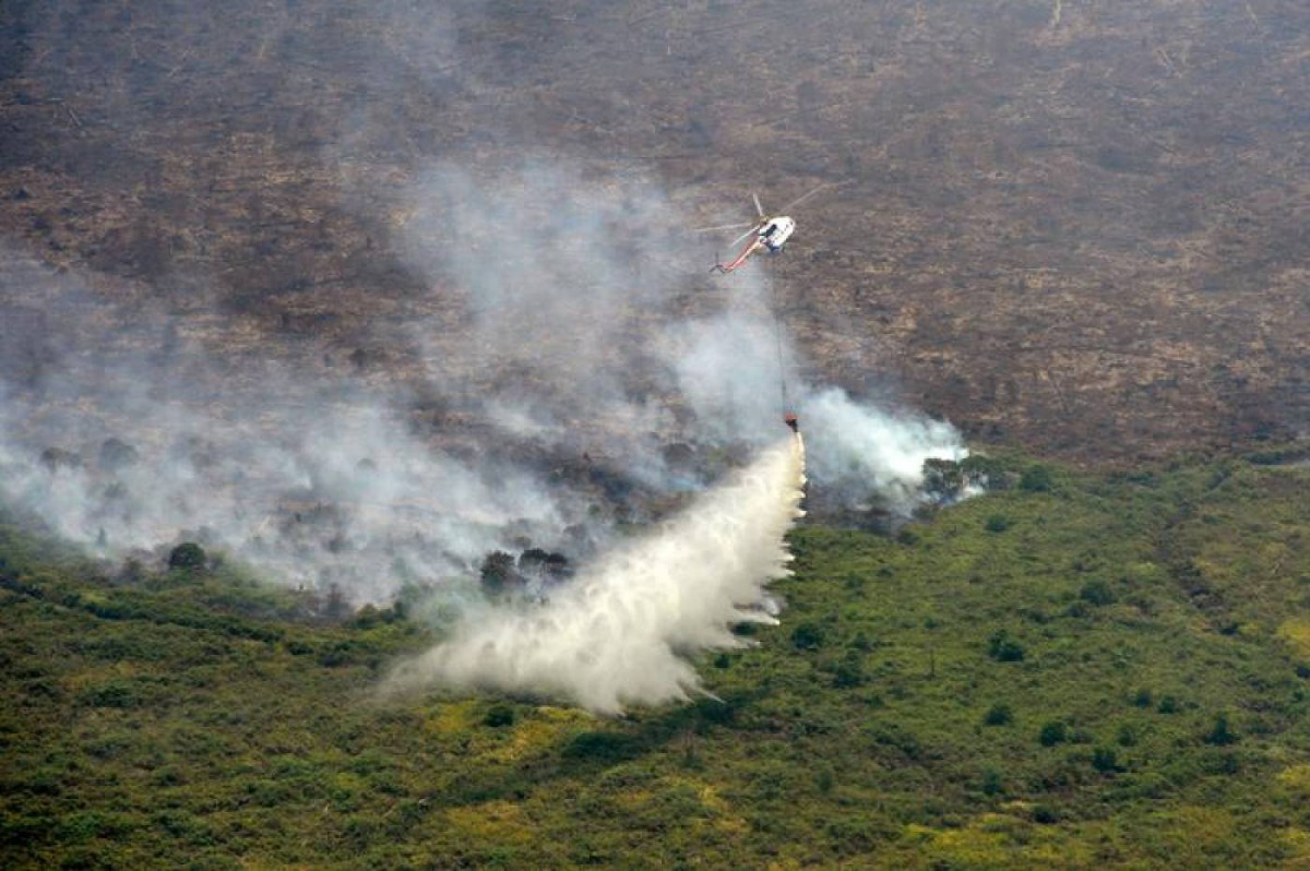 A Super Puma helicopter operated by Asia Pulp and Paper drops water on a burning forest in Musi Banyuasin near Palembang, South Sumatra province, Indonesia, August 21, 2019. Antara Foto/Wahdi Septiawan/via Reuters