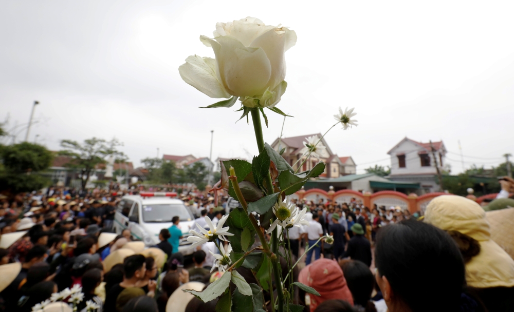Ambulances carrying the bodies of John Hoang Van Tiep and John Nguyen Van Hung, victims who were found dead in the back of a British truck last month, are surrounded by relatives and villagers in front of a church at homeland in Nghe An province, Vietnam 