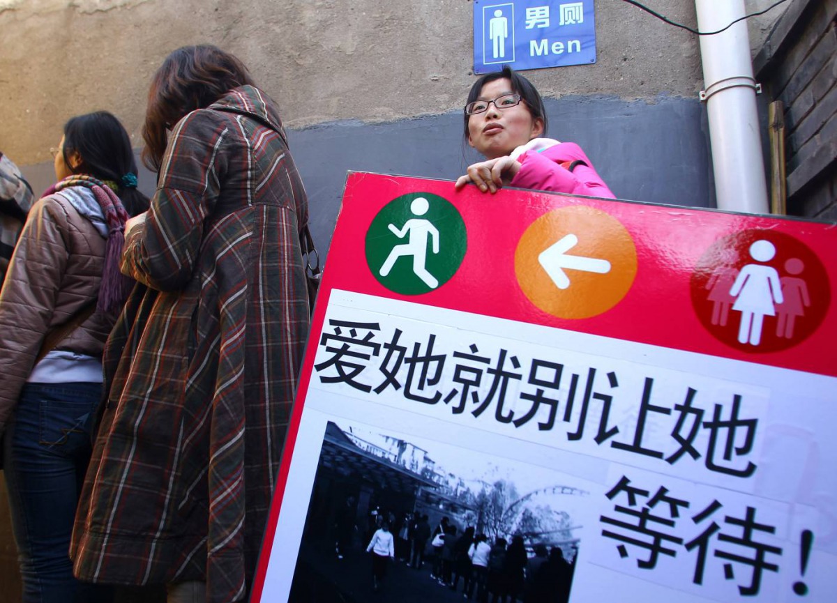 Women stand in line outside a men's toilet during a demonstration for more female sanitation facilities in Beijing, February 26, 2012. Reuters/China Daily