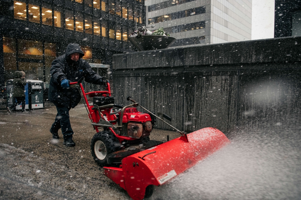 A building worker uses a snowblower to clear sidewalks in the Financial District as the first snowstorm of winter hits Manhattan on December 2, 2019 in New York. Scott Heins/Getty Images/AFP
