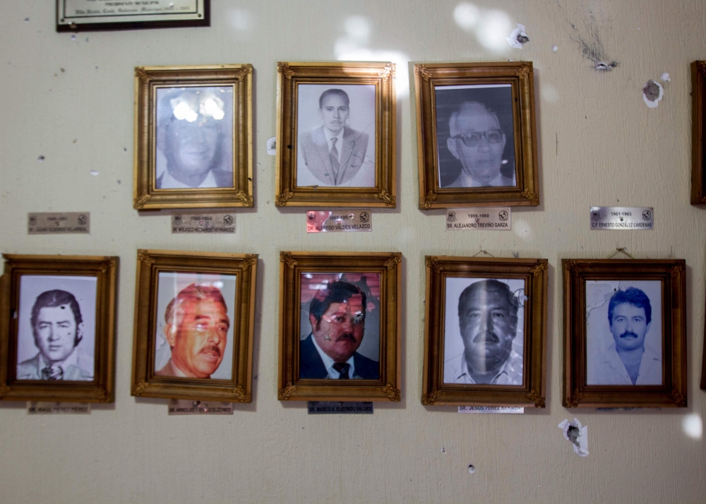 View of the bullet impacts in photographs of former municipal presidents with bullet impacts inside the municipal presidency in Villa Union, Coahuila state, Mexico, on December 2, 2019. AFP / Julio Cesar Aguilar
 