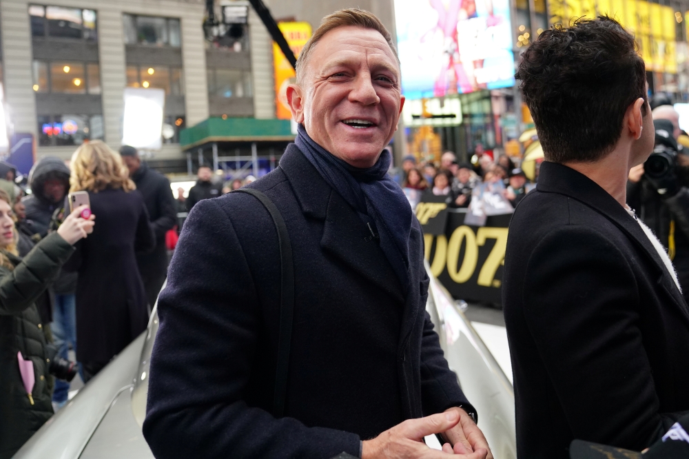 Actor Daniel Craig reacts next to actor Rami Malek during a promotional appearance on TV in Times Square for the new James Bond movie 