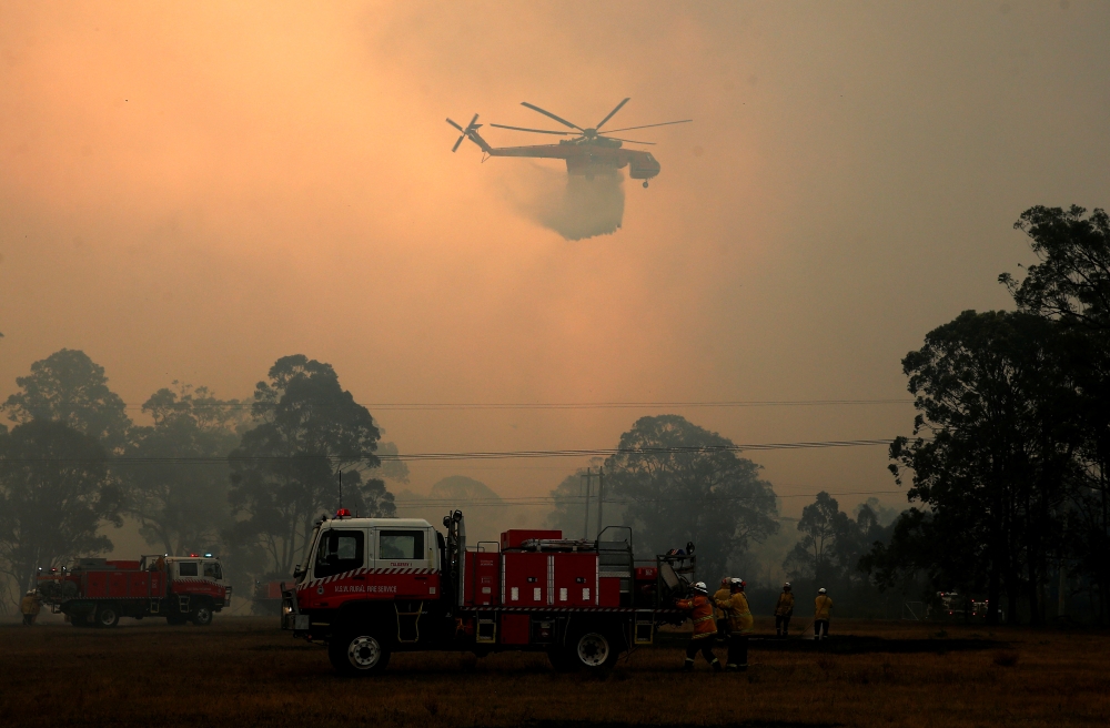 A firefighter talks on a radio as an out-of-control bushfire burns at Avery's Lane, Australia, December 3, 2019. Picture taken December 3, 2019. AAP Image/Darren Pateman/via REUTERS 