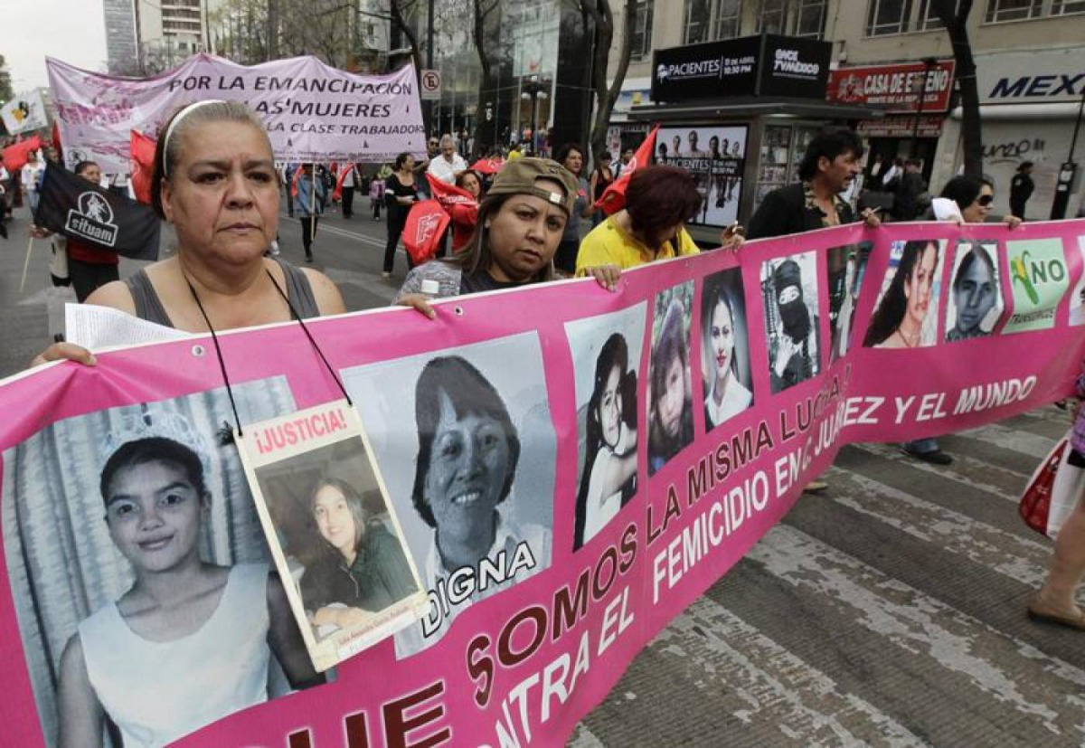 Norma Andrade Ledezma, a Mexican woman with a picture of her 17-year-old daughter who was murdered in Ciudad Juarez, walks with a banner during a protest demanding justice for the victims of violence at a closed street near Mexico's Interior Ministry buil