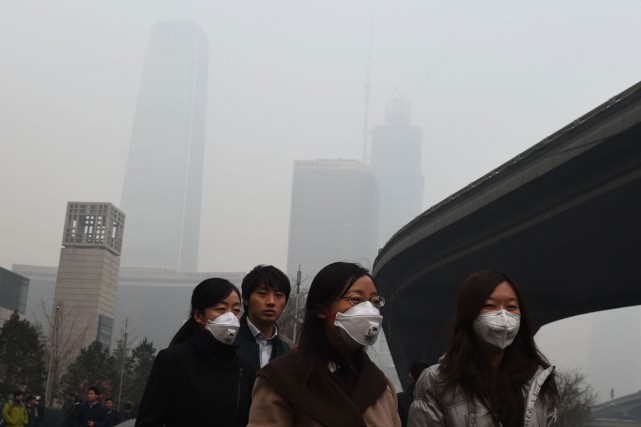 People wear masks on a polluted day in Beijing on December 9, 2015. AFP