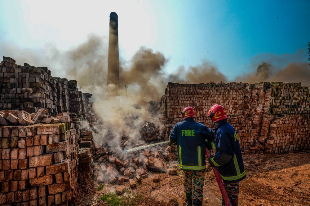 Firefighters extinguish the smoking bricks of an illegal brick factory being demolished following the decision of authorities from the Department Environment of the Ministry of Environment, Forest and Climate Change, on the outskirts of Dhaka on December 