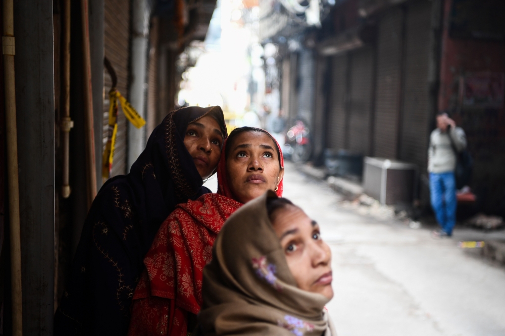  Women look at a factory site where a fire broke out a day before, in Anaj Mandi area of New Delhi on December 9, 2019. AFP / Sajjad Hussain
 