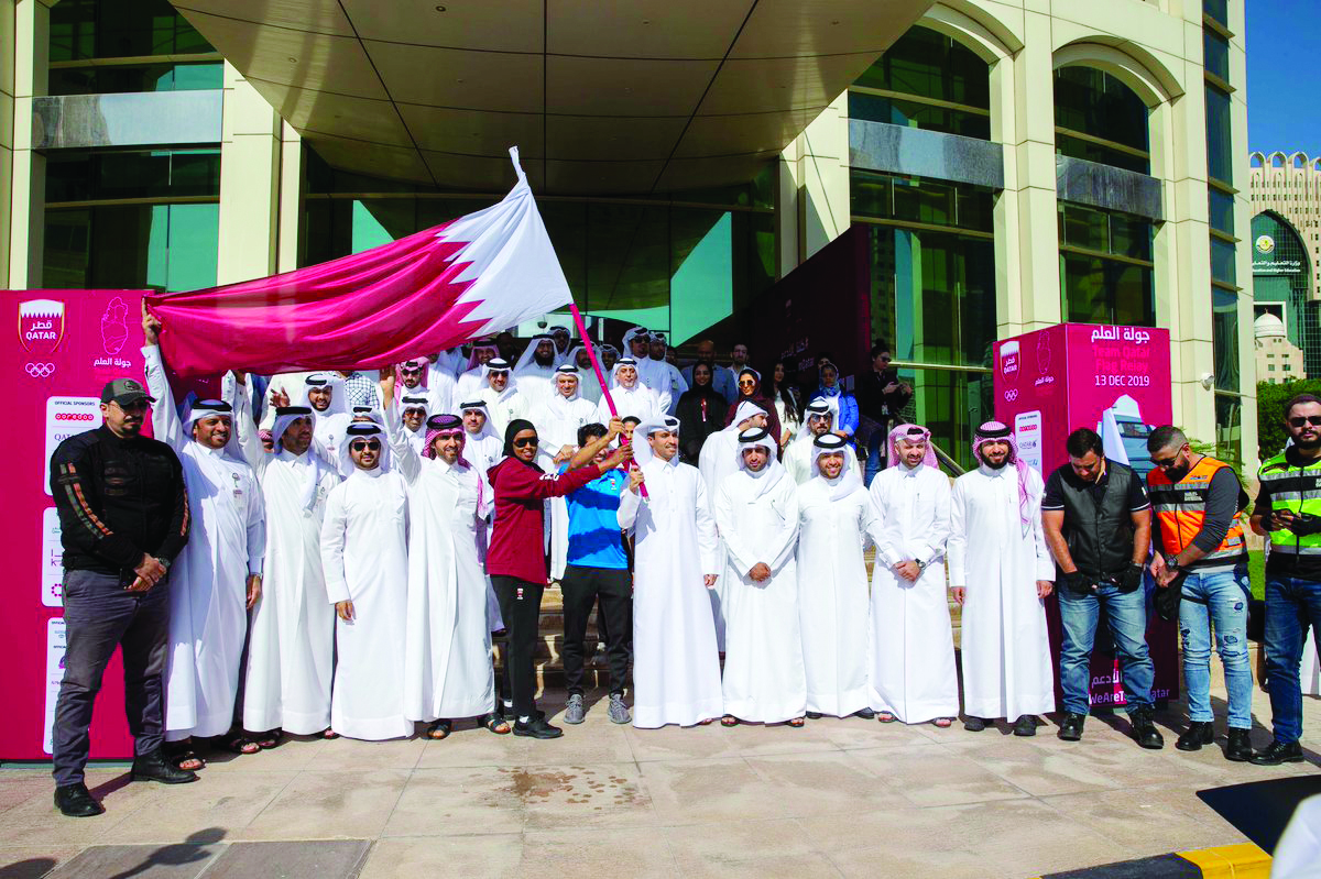 The QOC Secretary-General, officials and athletes posing for a photograph with the Qatar flag during the event.