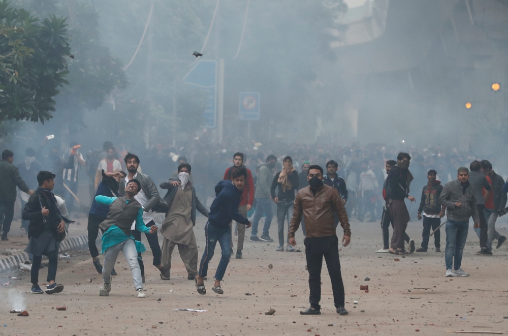 Protesters throw stones towards police during a protest against the Citizenship Amendment Bill outside the Jamia Millia Islamia University in New Delhi, India, December 13, 2019. Reuters/Adnan Abidi
 