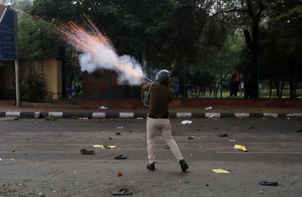 A police officer fires a teargas shell towards a protest against the Citizenship Amendment Bill outside the Jamia Millia Islamia University in New Delhi, India, December 13, 2019. REUTERS/Adnan Abidi