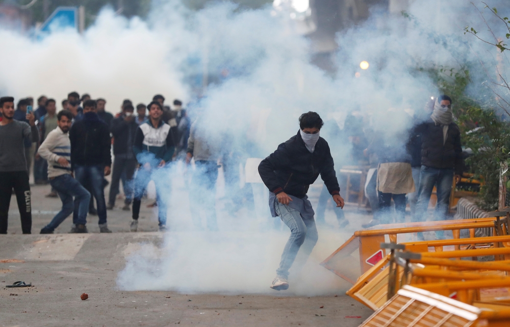 :FILE PHOTO: Protesters run for cover amid tear gas fired by police during a protest against the Citizenship Amendment Bill, a bill that seeks to give citizenship to religious minorities persecuted in neighbouring Muslim countries, outside the Jamia Milli