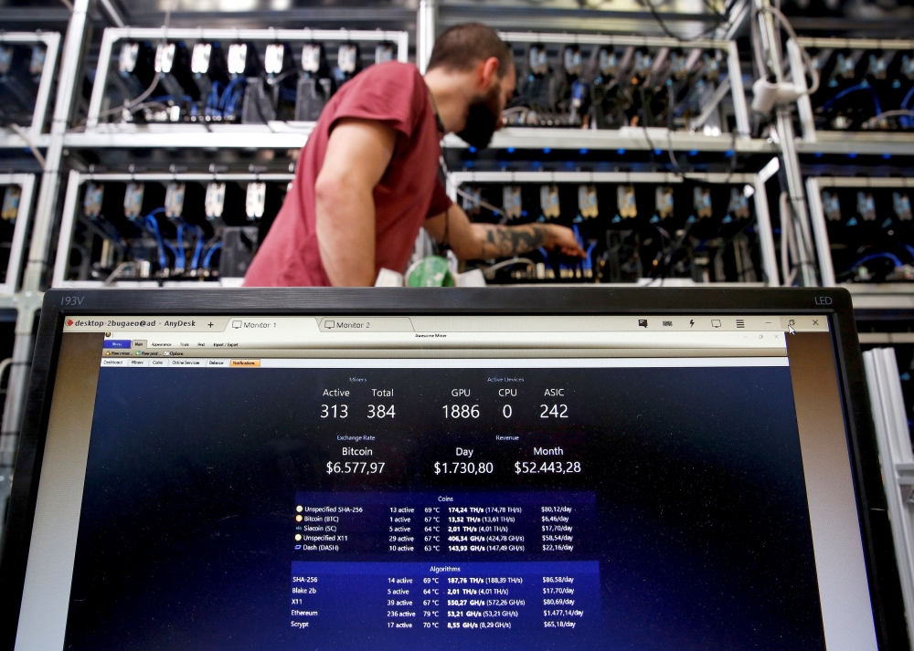An employee works on Bitcoin mining computer as a PC screen shows the fluctuations in Bitcoin exchange rates at Bitminer Factory in Florence, Italy, April 6, 2018. Reuters/Alessandro Bianchi