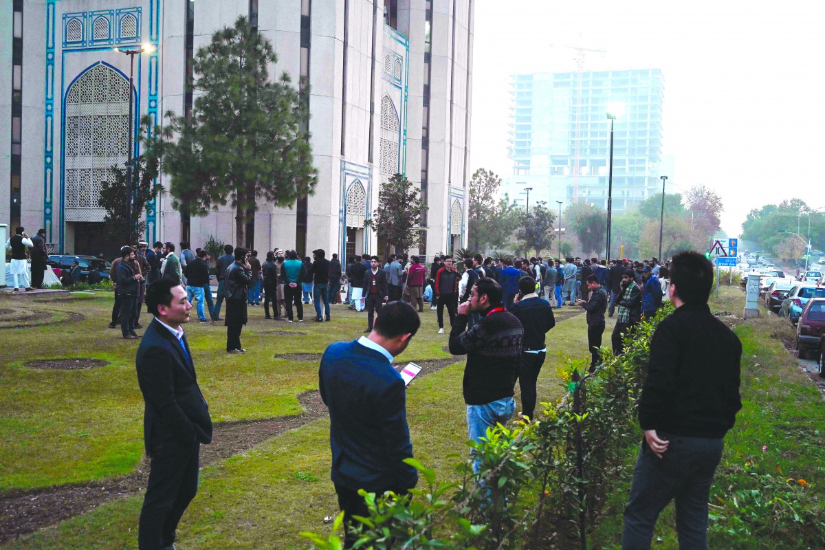 People gather outside buildings after a 6.1-magnitude earthquake in Islamabad on December 20, 2019. A strong earthquake rattled Afghanistan and Pakistan on December 20 afternoon, the US Geological Survey said, forcing residents into the streets in Islamab