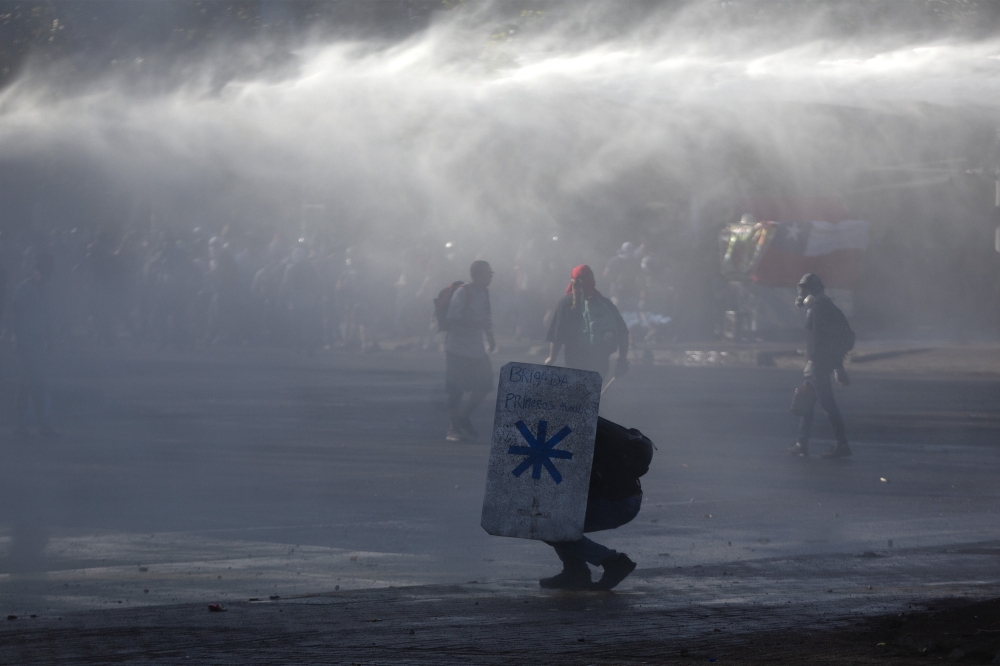 Riot police spray water to disperse demonstrators during a protest against Chilean President Sebastian Pinera's government in Santiago, on December 27, 2019.  AFP / CLAUDIO REYES