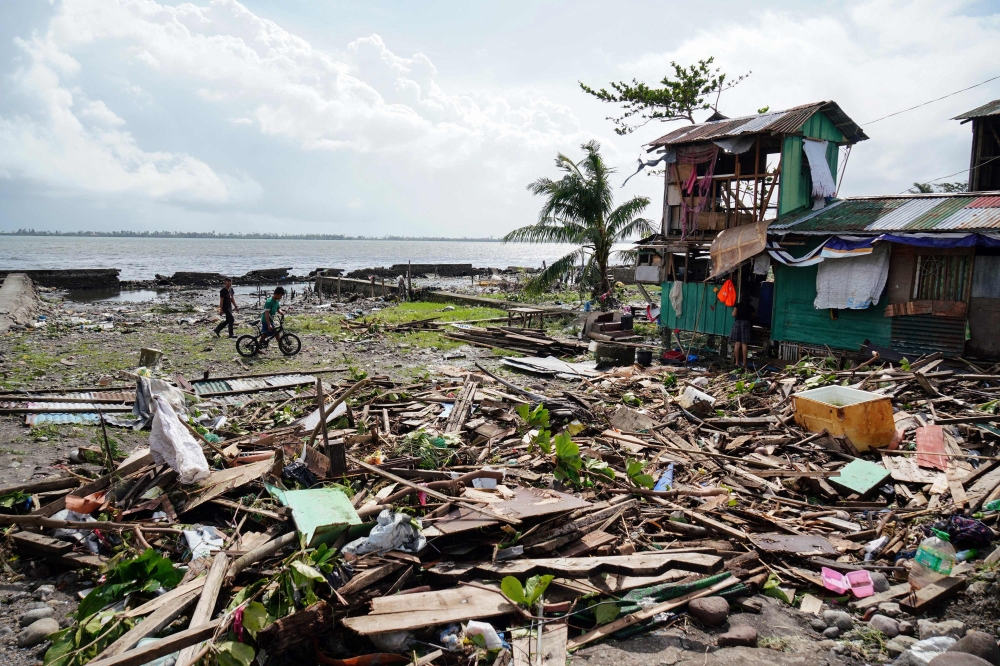 Residents walk past a house damaged during Typhoon Phanfone in Tacloban, Leyte province in the central Philippines on December 25, 2019. / AFP / Bobbie ALOTA 