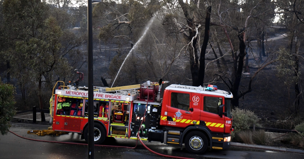 A fire truck dampens down a fire after a bushfire encroached on the outer suburbs of Melbourne. Australia. December 30, 2019 / AFP / William WEST
