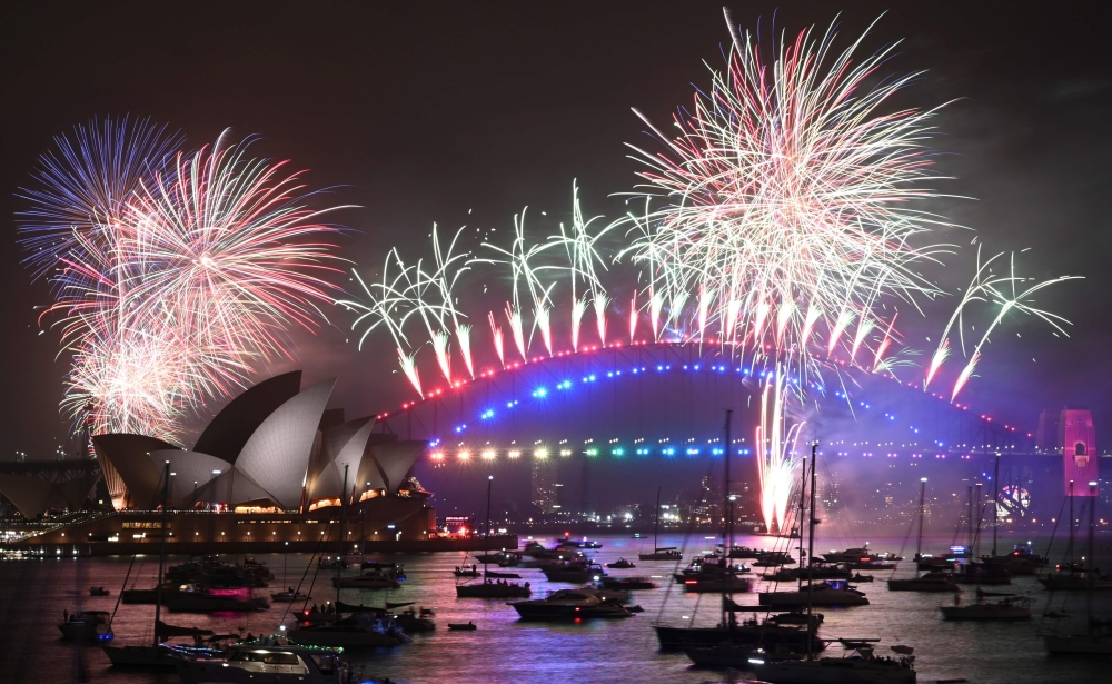 New Year's Eve fireworks erupt over Sydney's iconic Harbour Bridge and Opera House (L) during the fireworks show on January 1, 2020. AFP / Peter Parks
 