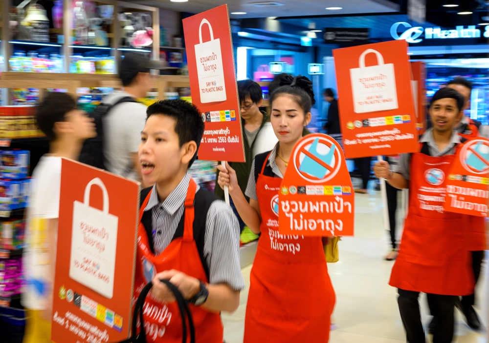 Employees carry banners informing customers about the ban on free single-use plastic bags at a shopping mall in downtown Bangkok on January 2, 2020. Thai retailers kicked off 2020 with a ban on free plastic bags to customers, as an environment group on Ja