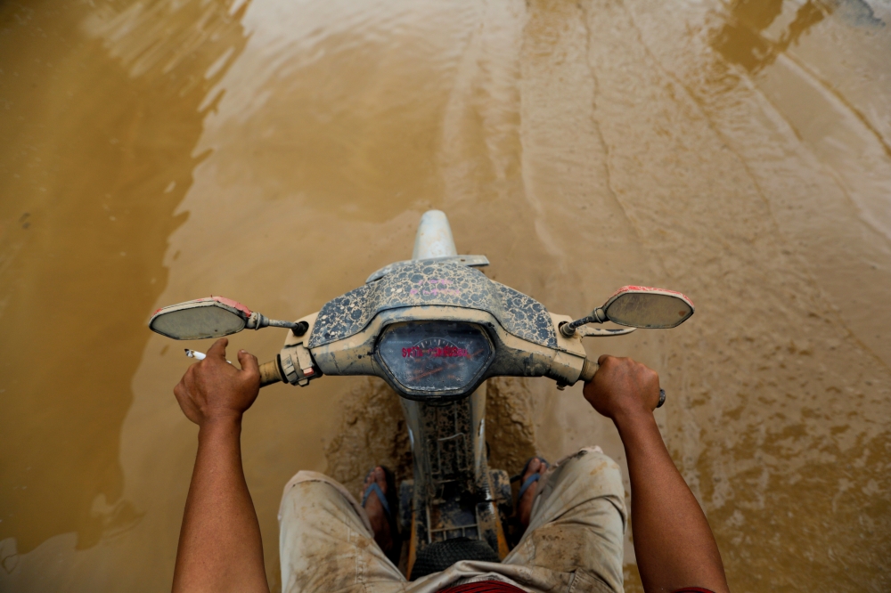 A man rides a motorbike through the mud after floods hit a residential area in Bekasi, West Java province, Indonesia, January 3, 2020. REUTERS/Willy Kurniawan