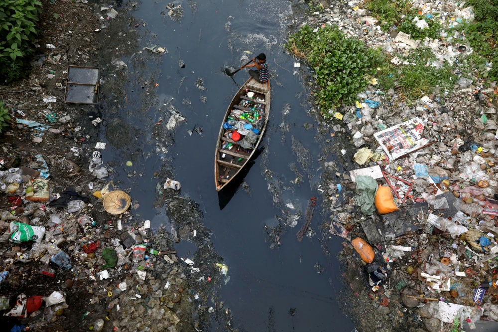 FILE PHOTO: A man on a boat collects plastic materials from dirty water in Dhaka, Bangladesh, April 17, 2019. REUTERS/Mohammad Ponir Hossain