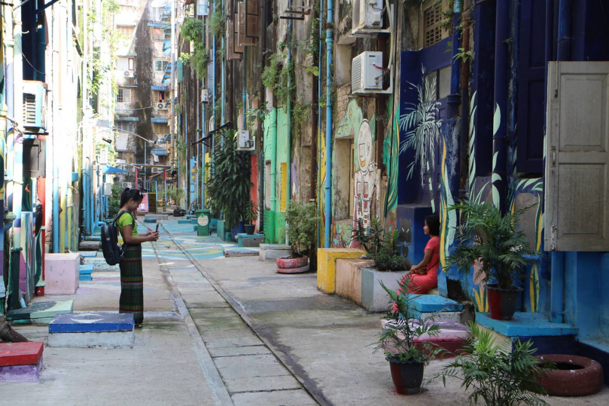 Visitors taking pictures at one of the back alleys that have been upgraded with the help of Doh Eain in downtown Yangon, Myanmar, on Nov 1, 2019. Thomson Reuters Foundation/Thin Lei Win
