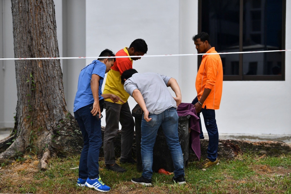 Police officers and cleaners inspect the contents of a bin at a rubbish chute, after a baby was found alive among rubbish in a bin at a public housing estate in Singapore, January 7, 2020. Lim Yaohui/The Straits Times via REUTERS