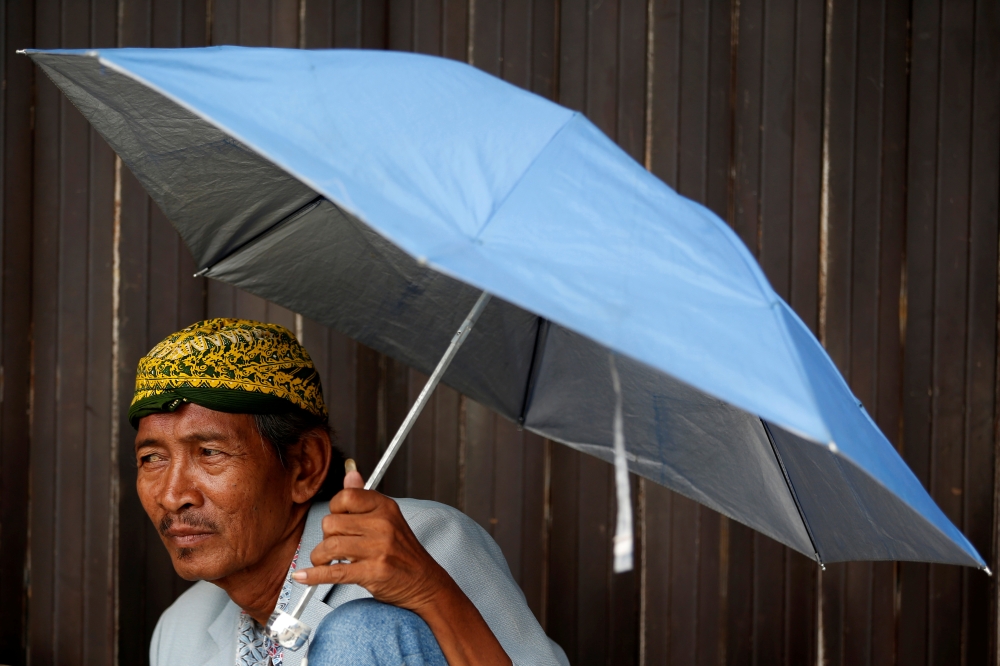A street vendor uses an umbrella as he waits for customers at a traditional market in Jakarta, Indonesia, June 3, 2019. Reuters / Willy Kurniawan