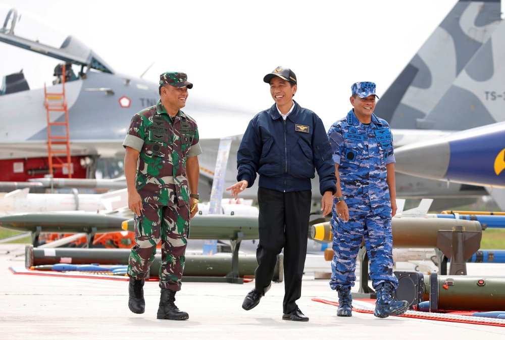 Indonesia's President Joko Widodo (C) along with Military Chief Gatot Nurmantyo (L) and Air Force Commander Agus Supriatna walk past fighter jets and weapons during a military exercise on Natuna Island, Riau Islands province, Indonesia October 6, 2016. RE