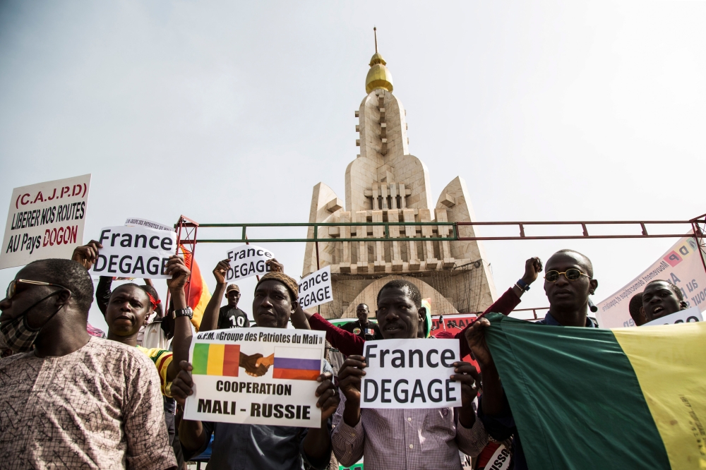 People hold up banners reading 'France get out' as they gather around the independence monument during a protest against French and UN forces based in Mali organized by Malian organization 'Yerewolo debout sur les remparts ' or 'Yerewolo standing on the r