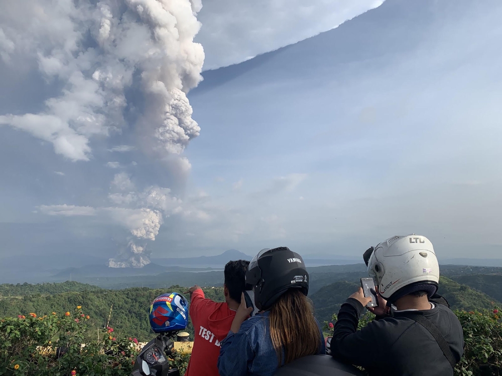 People take photos of a phreatic explosion from the Taal volcano as seen from the town of Tagaytay in Cavite province, southwest of Manila, on January 12, 2020. AFP / Bullit Marquez 