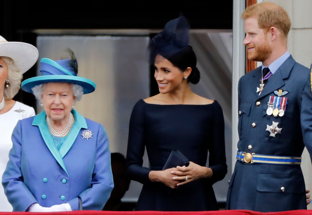 In this file photo taken on July 10, 2018 (L-R) Britain's Queen Elizabeth II, Meghan, Duchess of Sussex, Britain's Prince Harry, Duke of Sussex stand on the balcony of Buckingham Palace in London to watch a military fly-past to mark the centenary of the R