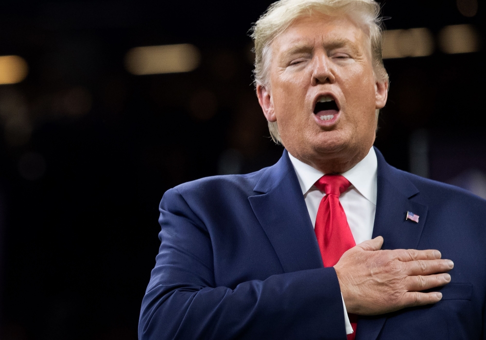 US President Donald Trump sings the National Anthem as he attends the College Football Playoff National Championship game at the Mercedes-Benz Superdome in New Orleans, Louisiana, January 13, 2020. / AFP / SAUL LOEB