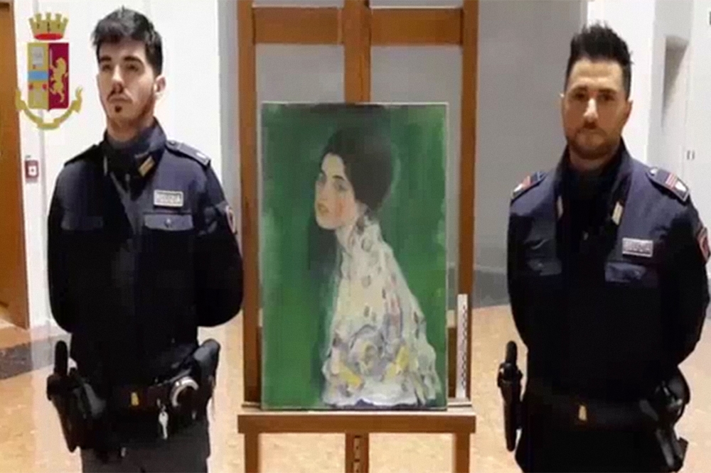 Police officers standing by a painting stolen over 20 years ago and which by initial indications was painted by Gustav Klimt found by chance in Piacenza museum gardens in northern Italy AFP Polizia Di Stato (Italian State Police video grab on December 12,