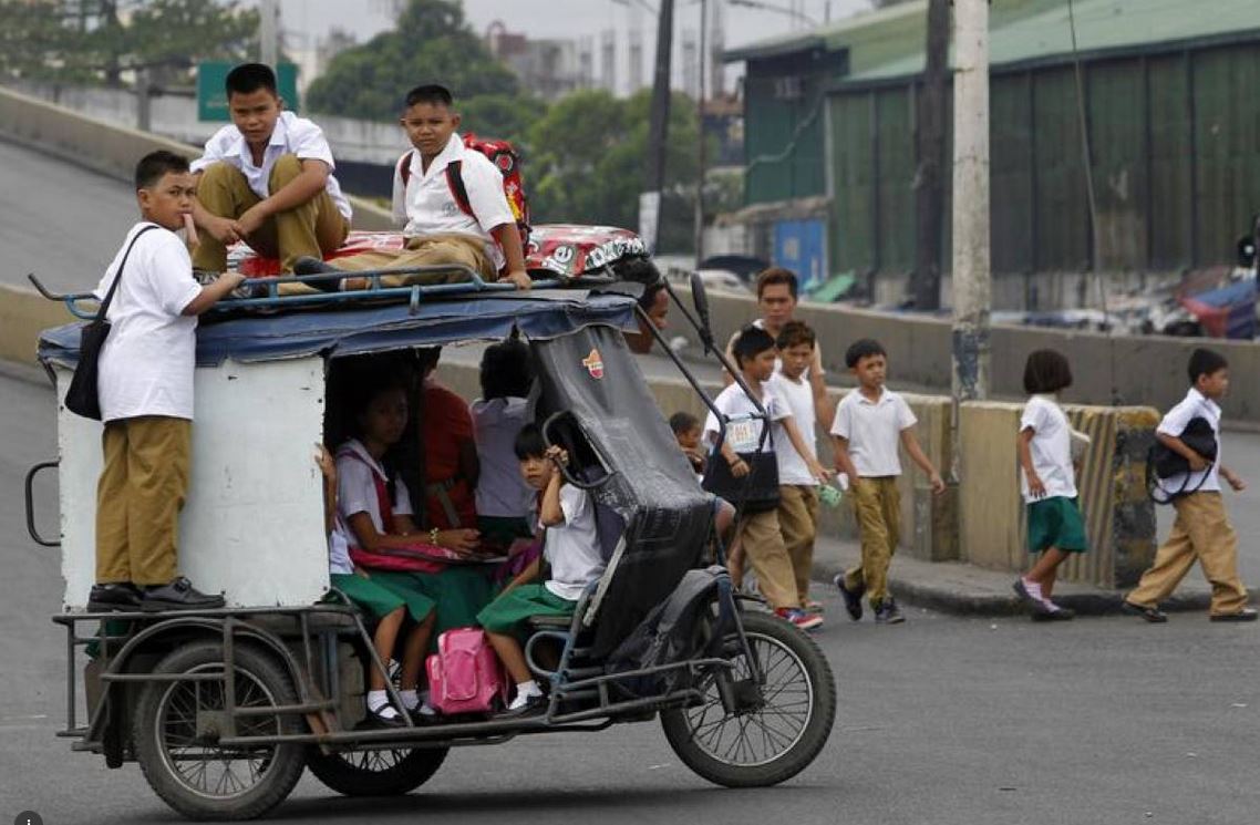 Children sit on top of a tricycle cab as they make their way to school along a main street in Tondo city, metro Manila June 4, 2012. Reuters/Romeo Ranoco