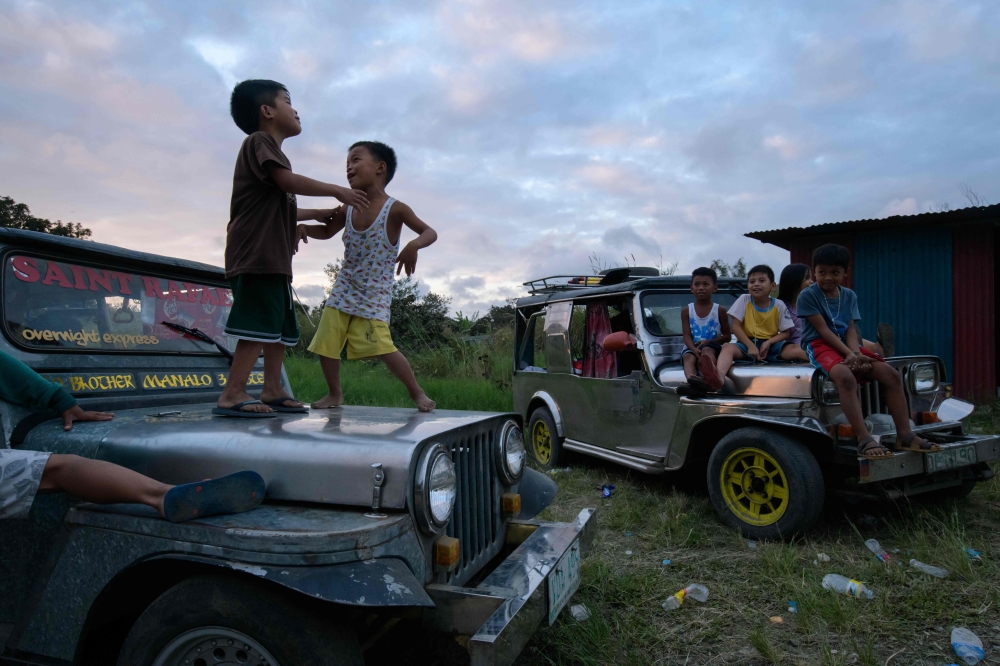 Children displaced by the Taal volcano eruption play on vehicles at a government complex used as an evacuation centre in Tagaytay on January 18, 2020. / AFP / Ed JONES