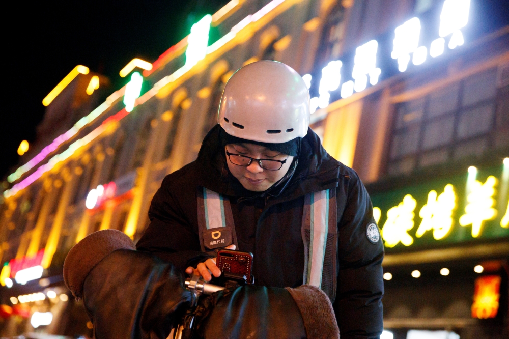 Liu Pengfei, a substitute driver of DiDi Chuxing, checks the ride-hailing app before starting his night shift in Beijing, China January 10, 2020. REUTERS/Thomas Peter