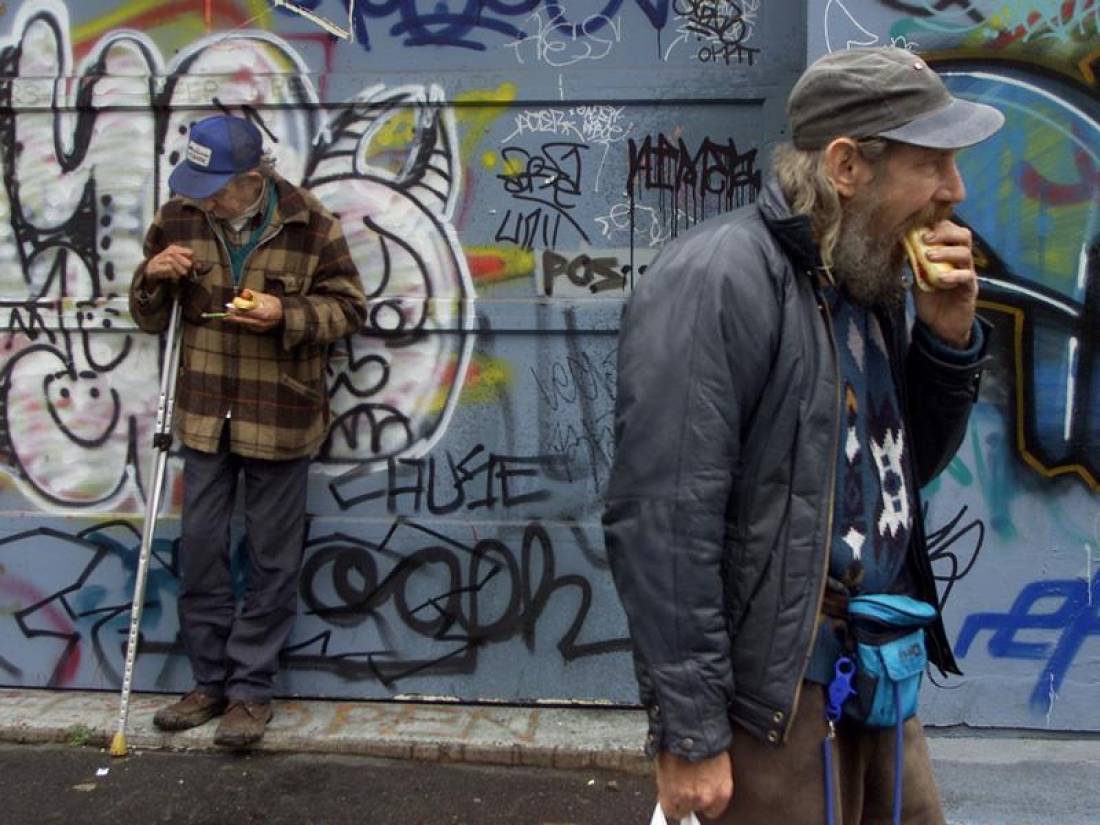 Homeless men eat hot dogs handed out from a soup kitchen handed out in a vacant lot in downtown Vancouver, November 22, 2001. Reuters/Andy Clark