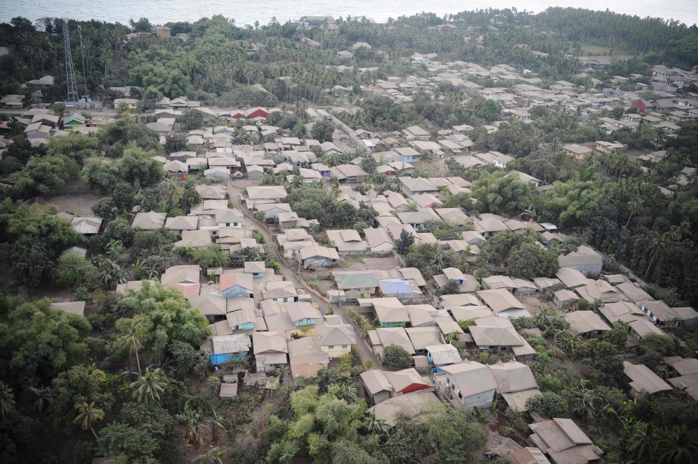 A bird's eye view of mud-covered and destroyed houses with Taal volcano in background as seen from a Philippine airforce helicopter during an aerial survey in Agoncillo town, Batangas province, south of Manila on January 21, 2020. / AFP / Ted ALJIBE 