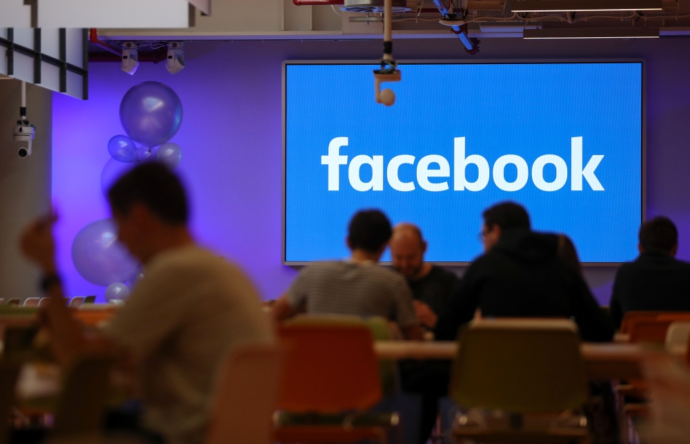 FILE PHOTO: Employees have lunch at the canteen at Facebook's new headquarters, designed by Canadian-born American architect Frank Gehry, at Rathbone Place in central London.  AFP / Daniel LEAL-OLIVAS