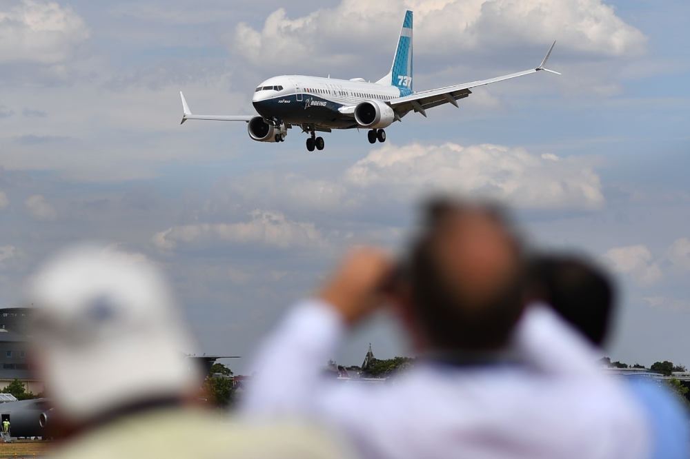 Visitors watch as a Boeing 737 Max lands after an air display during the Farnborough Airshow, south west of London on July 16, 2018. AFP / Ben Stansall