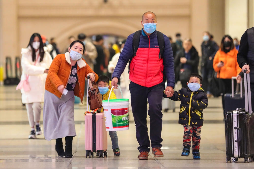 Commuters wearing face masks walk in Hankou railway station in Wuhan, in China's central Hubei province on January 21, 2020. Asian countries on January 21 ramped up measures to block the spread of a new virus as the death toll in China rose to six and the