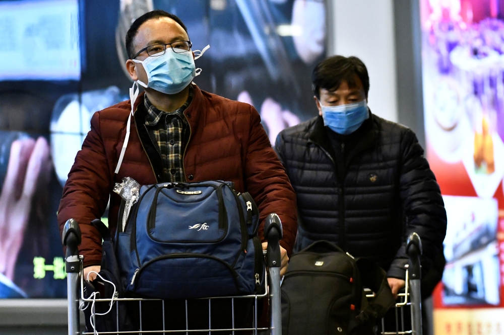 Travellers, wearing masks, arrive on a direct flight from China, after Canada's Public Health Agency added a screening question for visitors and began displaying messages in several airports urging travellers to report flu-like symptoms in efforts to prev