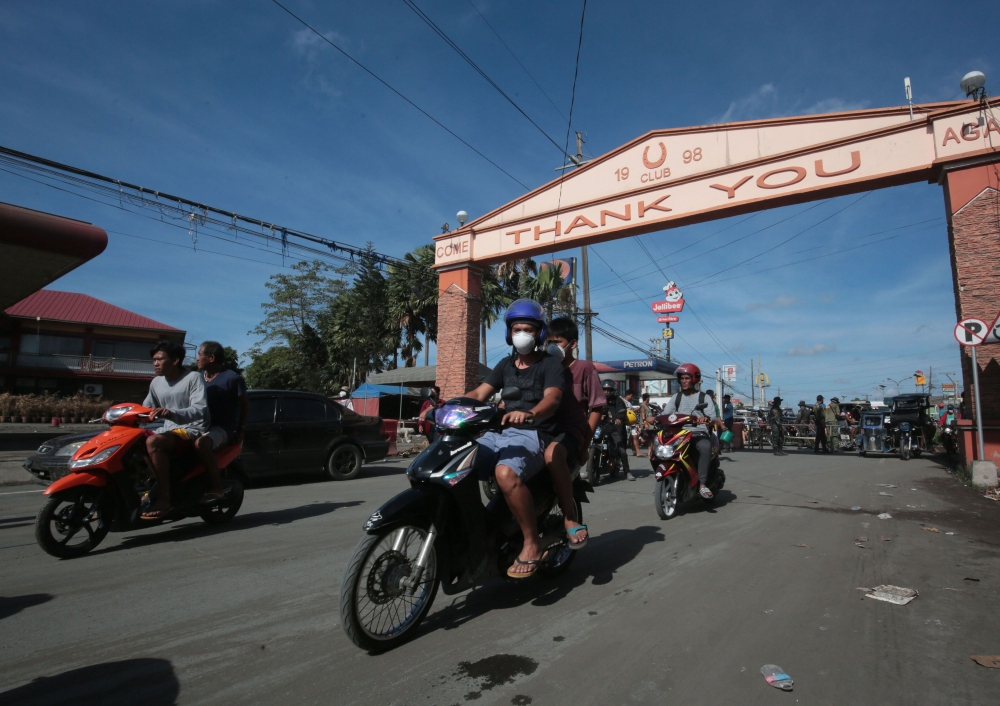 Residents on motorcycles ride back to their homes after the Philippine volcanology bureau lowered the alert level from 4 to 3 and residents were allowed to return home in the town of Lemery, Batangas province, south of Manila on January 26, 2020. A major 
