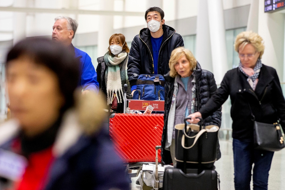 Travellers wear masks at Pearson airport arrivals, shortly after Toronto Public Health received notification of Canada's first presumptive confirmed case of coronavirus, in Toronto, Ontario, Canada January 25, 2020. REUTERS/Carlos Osorio