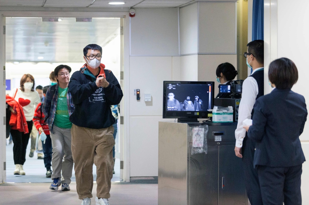 This picture taken on January 13, 2020 shows Taiwan's Center for Disease Control (CDC) personnel (R) using thermal scanners to screen passengers arriving on a flight from China's Wuhan province, where a SARS-like virus was discovered and has since spread,