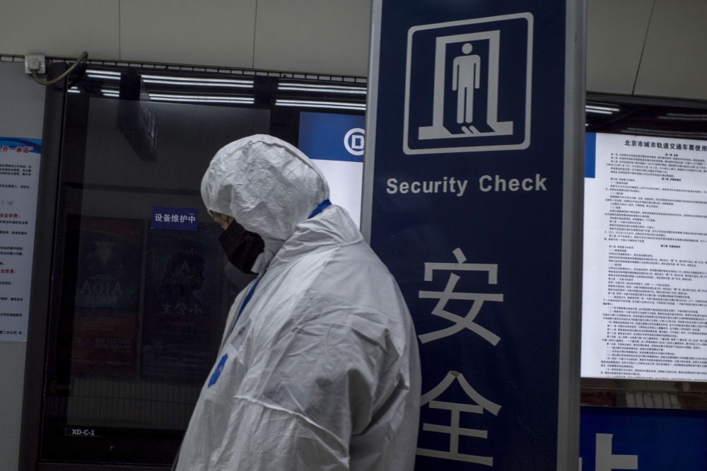 Security personnel wearing protective clothing to help stop the spread of a deadly virus which began in Wuhan, stands at a subway station in Beijing on January 26, 2020. AFP / NOEL CELIS