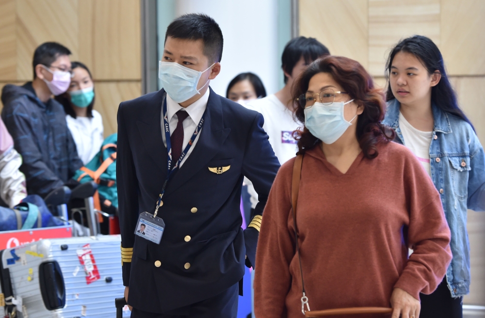 A China Eastern Airlines pilot and passangers arrive at Sydney airport after landing a plane from Shanghai on January 25, 2020. Australian authorities confirmed its first case of a new virus as thousands of people worldwide are treated for the deadly infe